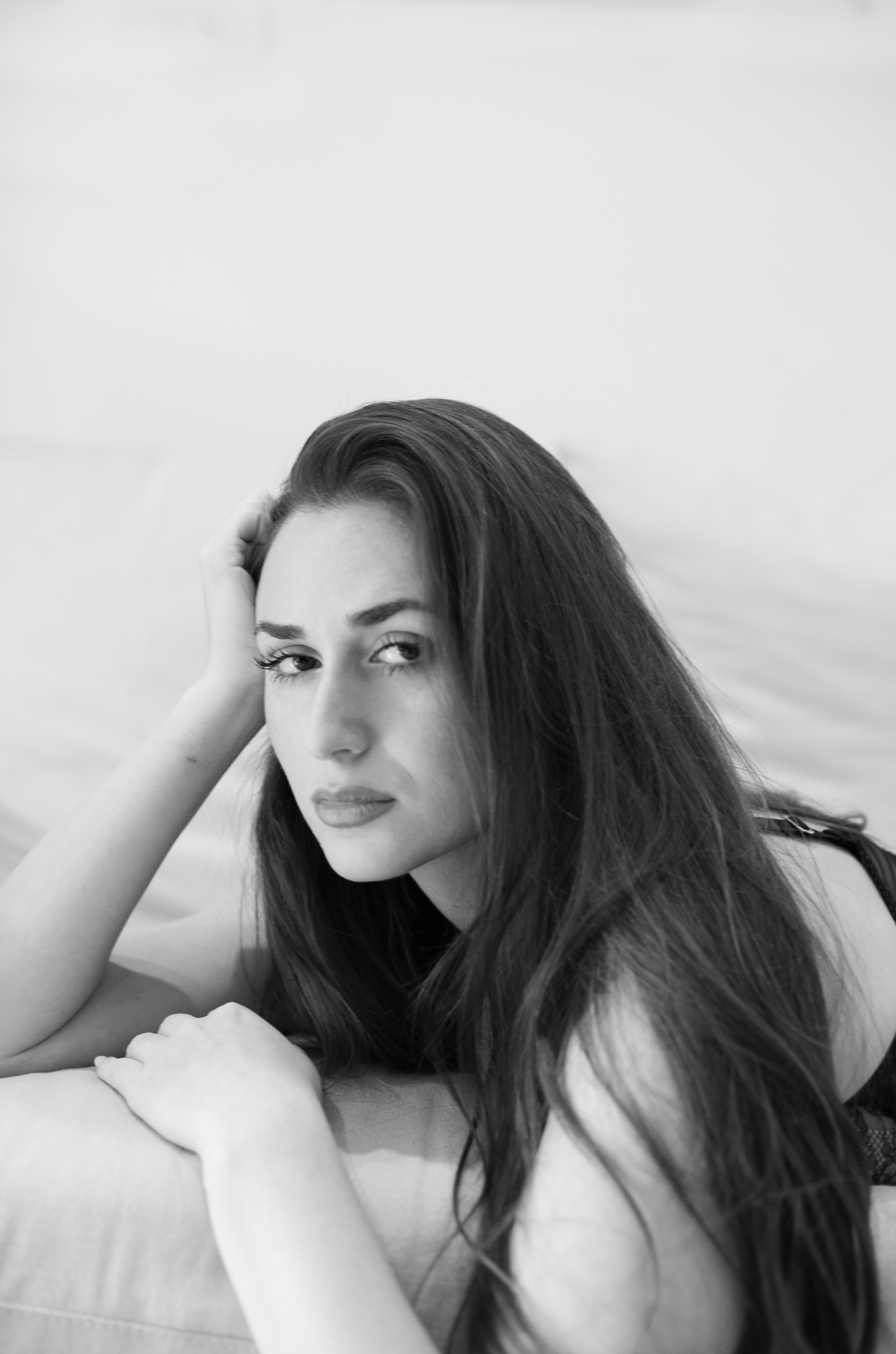 black and white portrait of dark haired model lying on sofa